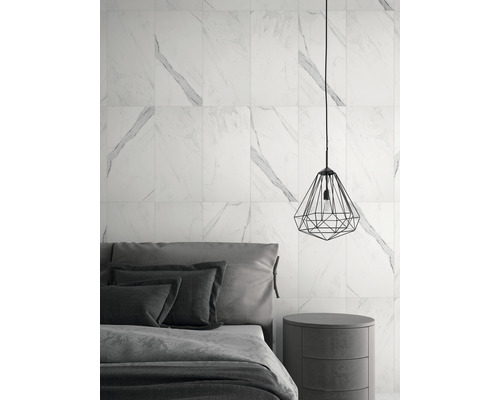 Dormitor cu gresie de perete cu aspect de marmură, noptieră și lampă