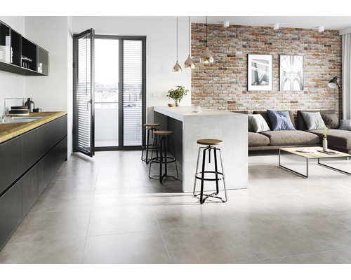 Spațiu de locuit luminos cu bucătărie, scaune de bar, podea cu gresie și perete din cărămidă