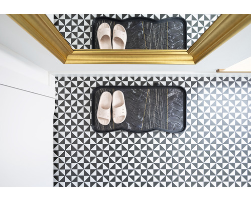 Hol cu suport pentru pantofi și papuci în fața unui perete cu model geometric