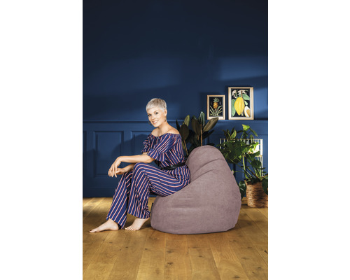 Femeie așezată pe un sac de fasole gri într-o cameră de zi.