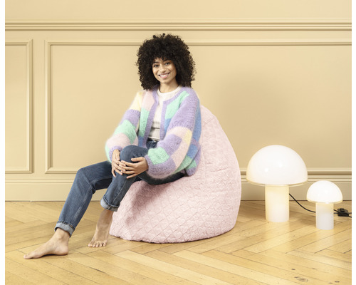 Femeie stând pe un sac roz lângă două lămpi în formă de ciupercă