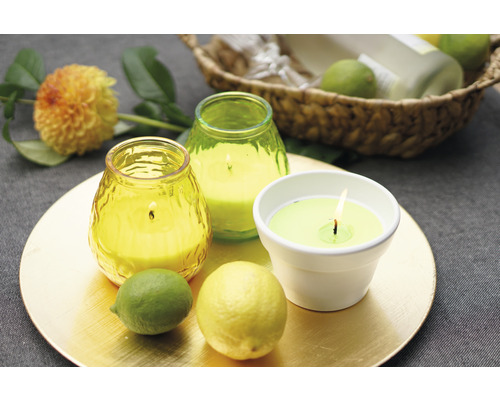 Aranjament decorativ cu lumânări parfumate, lămâie și lime pe o farfurie aurie.