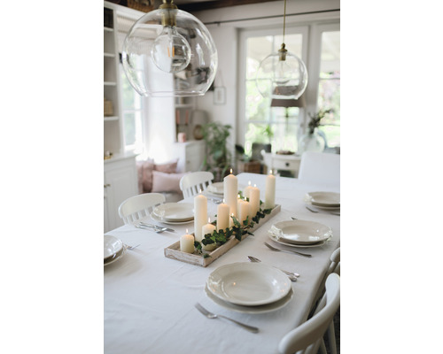 Masa de sufragerie aranjată cu sfeșnic, veselă și decorațiuni într-o cameră luminoasă.