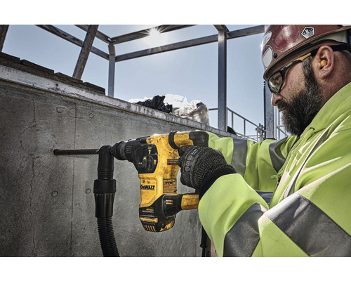 Un muncitor în construcții găurește un perete de beton cu un ciocan rotopercutor DeWalt.