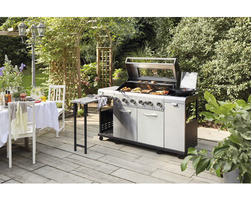 Scenă de grătar în aer liber cu grătar mare, masă de grădină și scaune pe o terasă