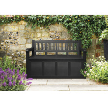 Bancă de grădină cu spațiu de depozitare în fața unui zid de piatră cu plante