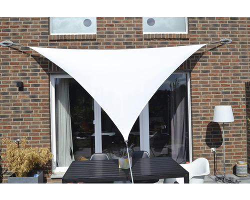 Pânză de umbrire triunghiulară în fața unui perete de casă cu mobilier de terasă