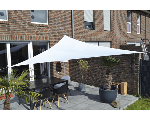 Zonă de relaxare în aer liber cu pânză de umbrire, masă și scaune în fața unei case de cărămidă