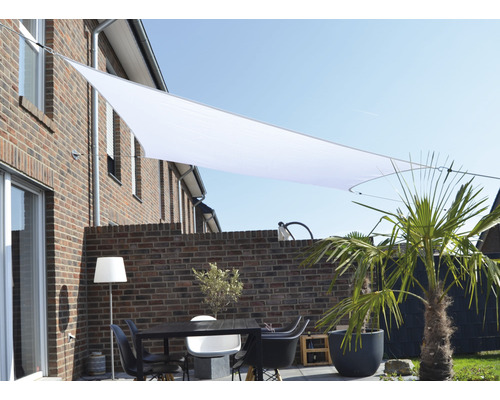 Terasa cu pânză de umbrire, masă și scaune în fața unui zid de cărămidă