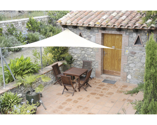 Terasa cu pânză de umbrire, masă de grădină și scaune în fața unei case de piatră