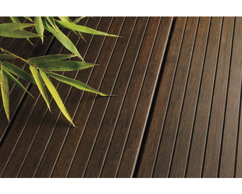 Prim-plan cu scânduri de terasă din lemn cu ramură de bambus