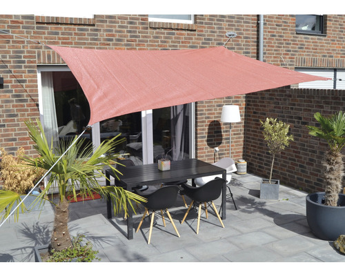 Terasa cu pânză de umbrire, masă și scaune în fața unei clădiri din cărămidă