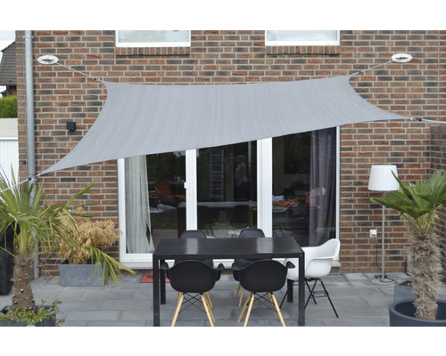 Terasa cu pânză de umbrire, masă și scaune în fața unui zid de casă