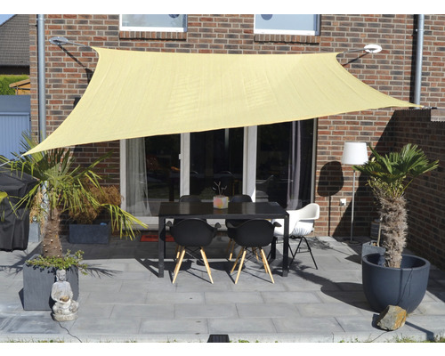 Terasa cu pânză de umbrire, masă și scaune în fața unei clădiri din cărămidă