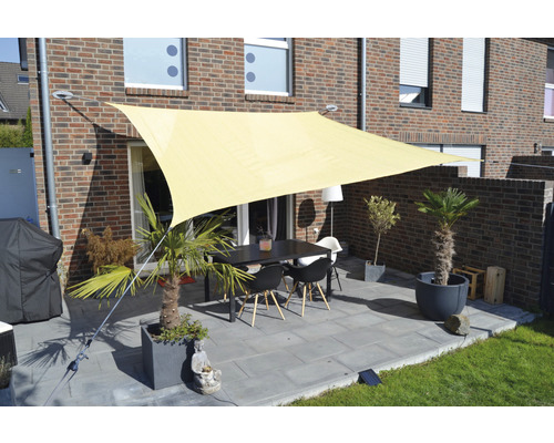 Terasa cu pânză de umbrire, masă și scaune în fața unei case de cărămidă