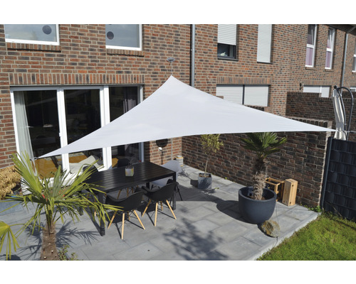 Terasa cu pânză de umbrire triunghiulară, masă și scaune în fața unei case de cărămidă