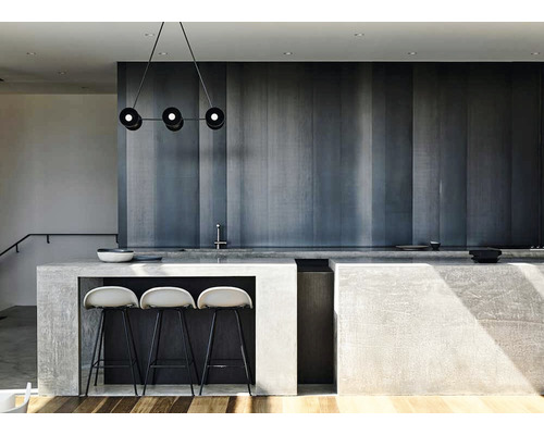 Design modern de bucătărie cu o lustră suspendată, blat de beton și scaune de bar.