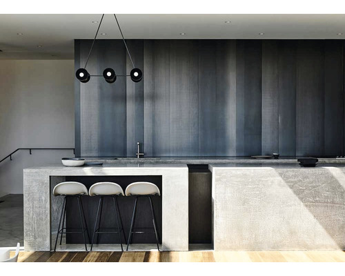 Bucătărie luminoasă cu insulă, scaune de bar și corp de iluminat suspendat.