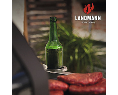 Scenă de grătar cu sticlă de băutură și bucăți de carne pe grătar, logo-ul Landmann