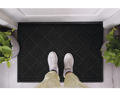 Covoraș negru cu model geometric în fața unei uși