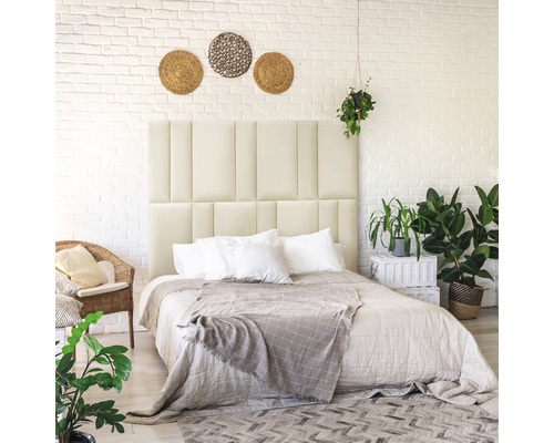 Dormitor cu tăblie tapițată, lenjerie de pat și decorare în fața unui perete din cărămidă albă.