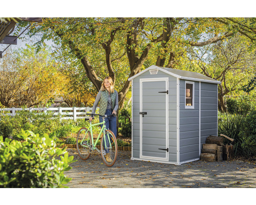 Scenă de grădină cu magazie de grădină, bicicletă și femeie în grădină