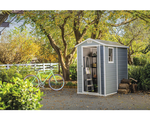 Scenă de grădină cu șopron de scule, bicicletă, scară, raft și stivă de lemne