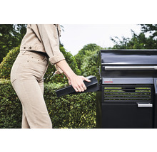 Femeie introducând bateria în grătarul electric.