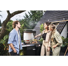 Oameni care fac grătar în grădină cu un grătar pe gaz.