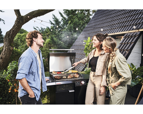 Oameni care fac grătar în grădină cu un grătar pe gaz.