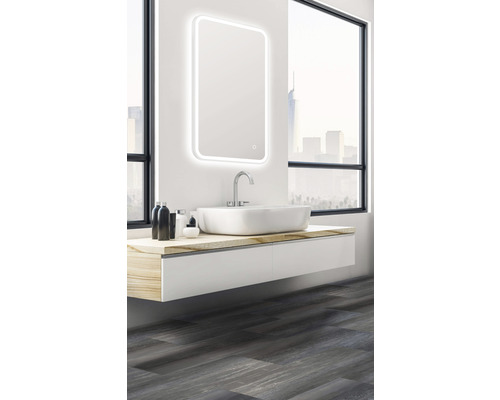 Baie cu oglindă iluminată, chiuvetă și dulap inferior în fața unei ferestre.