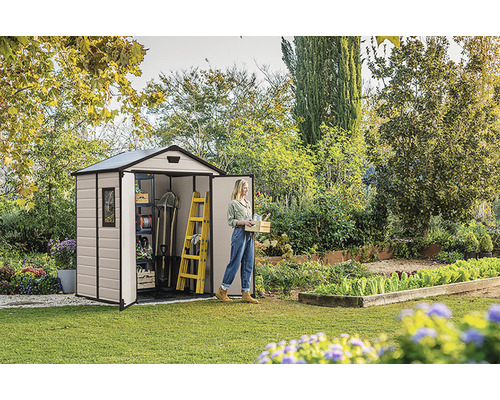 Scenă de grădină cu o magazie de scule, o femeie și unelte de grădină.