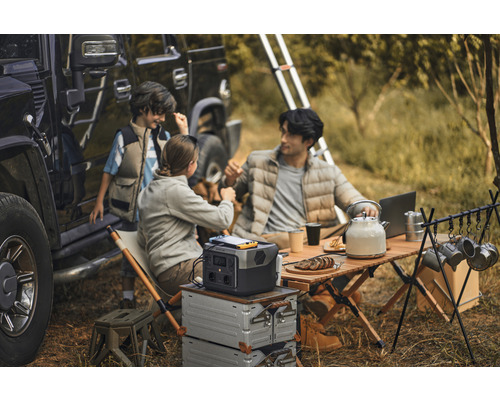 Camping familial cu stație de alimentare portabilă, masă și accesorii lângă un vehicul de teren