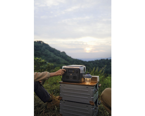 Persoană care operează o stație de alimentare portabilă într-o excursie de camping