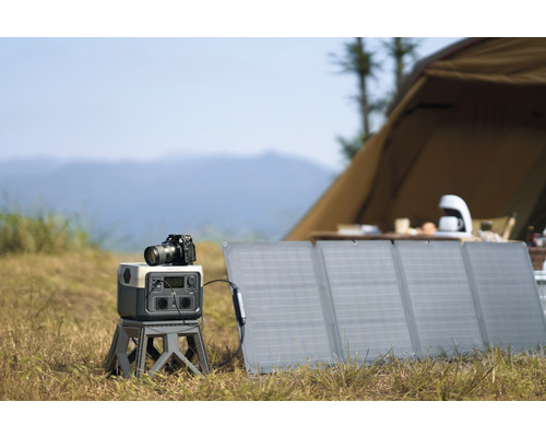 Scenă de fotografie în aer liber cu panou solar, generator de curent și cameră în fața unui cort