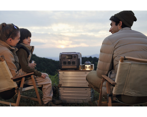 Familie stă în camping cu stație de alimentare portabilă și lampă