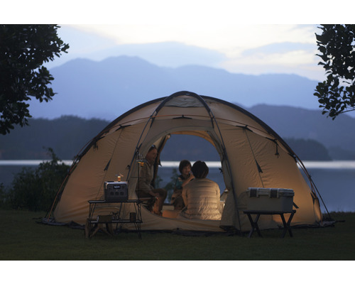 Scenă cu cort de camping, cutie frigorifică, masă și stație de alimentare portabilă în natură