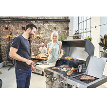 Oameni care fac grătar carne și legume pe un grătar cu gaz în aer liber.