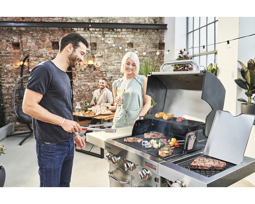 Oameni care fac grătar carne și legume pe un grătar cu gaz în aer liber.