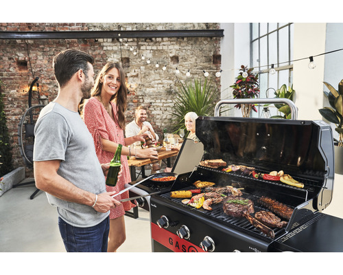 Oameni care fac grătar fripturi, legume și fructe de mare pe un grătar cu gaz în aer liber.