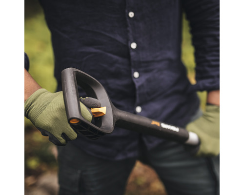 O persoană ține în mână o lopată Fiskars neagră cu mâner și lamă, în timp ce poartă mănuși.