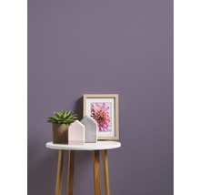 Scenă decorativă cu plantă în ghiveci, decorațiuni pentru casă și o imagine înrămată pe o măsuță în fața unui perete
