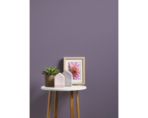 Scenă decorativă cu plantă în ghiveci, decorațiuni pentru casă și o imagine înrămată pe o măsuță în fața unui perete