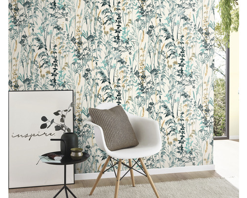 O cameră cu tapet floral în tonuri albastru-verzui și bej, un scaun alb cu o pernă, o măsuță laterală cu decorațiuni și un tablou.