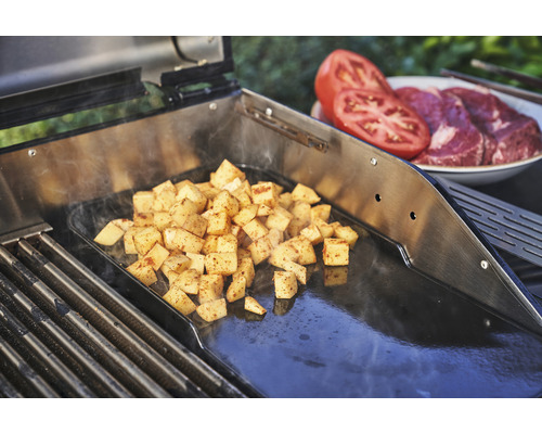 Cuburi de cartofi preparați pe o plită lângă roșii și carne