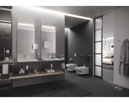 Baie modernă cu chiuvete, oglinzi, toaletă și bideu.