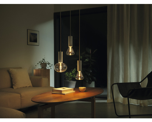 Living cu trei corpuri de iluminat suspendate deasupra unei măsuțe de cafea