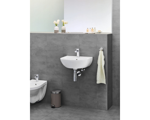 Baie cu lavoar, bideu, coș de gunoi și suport pentru prosop pe un perete gri