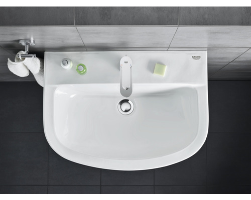 Vedere de sus a unei chiuvete cu robinet, săpun, prosop și produse de îngrijire în baie