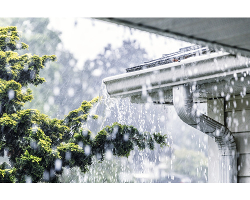 Apa de ploaie curge de pe un acoperiș într-o jgheab